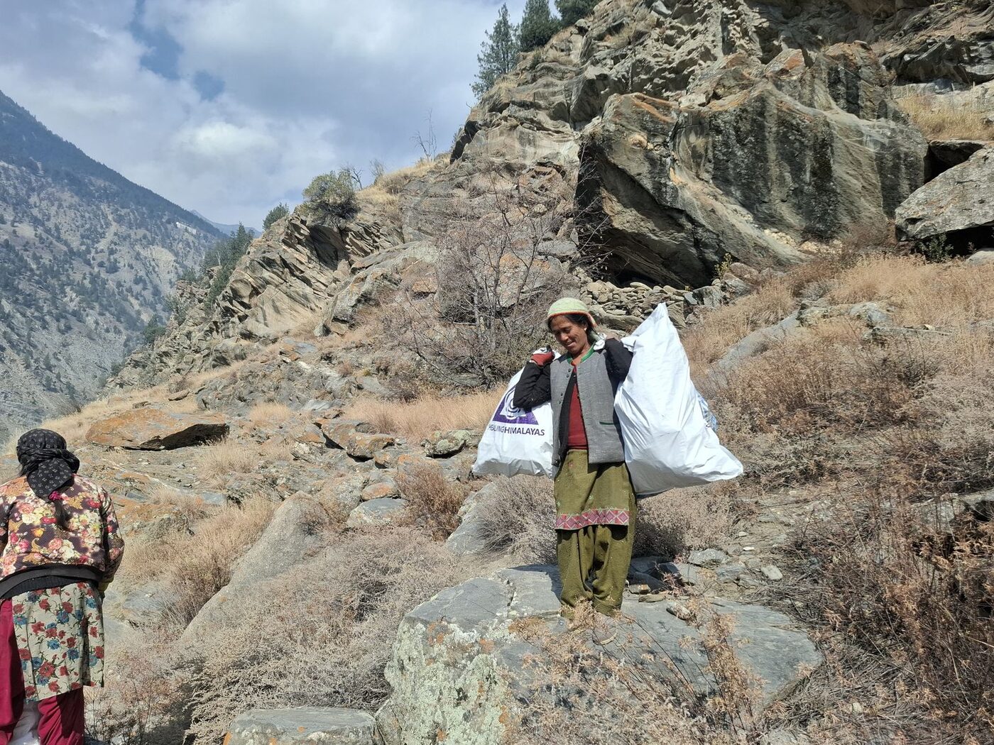 Himachali women carrying sacks of collected waste along a mountain trail